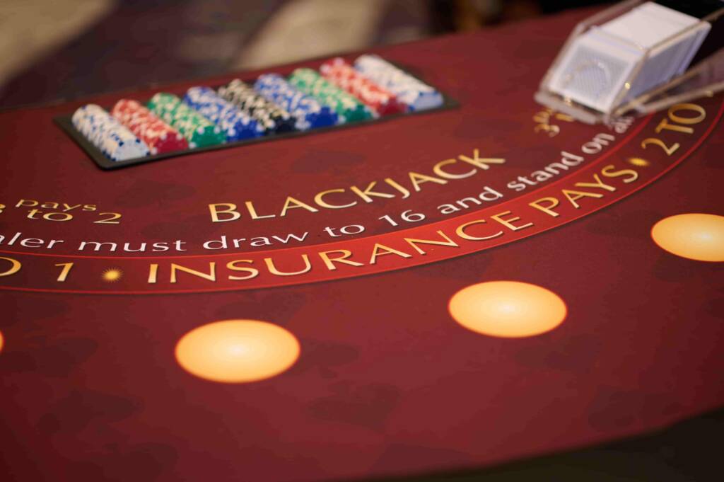 A casino table reads the word "Blackjack" with various different chips stacked nearby and a deck of cards.