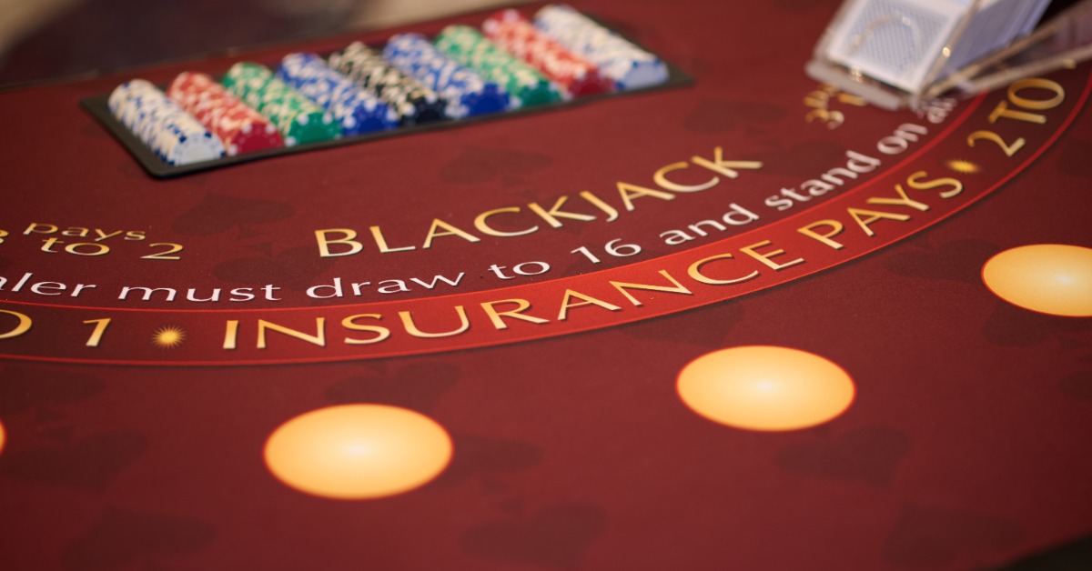 A blackjack table fills the frame as colorful chips and a card shoe sit across the red felt during an event.