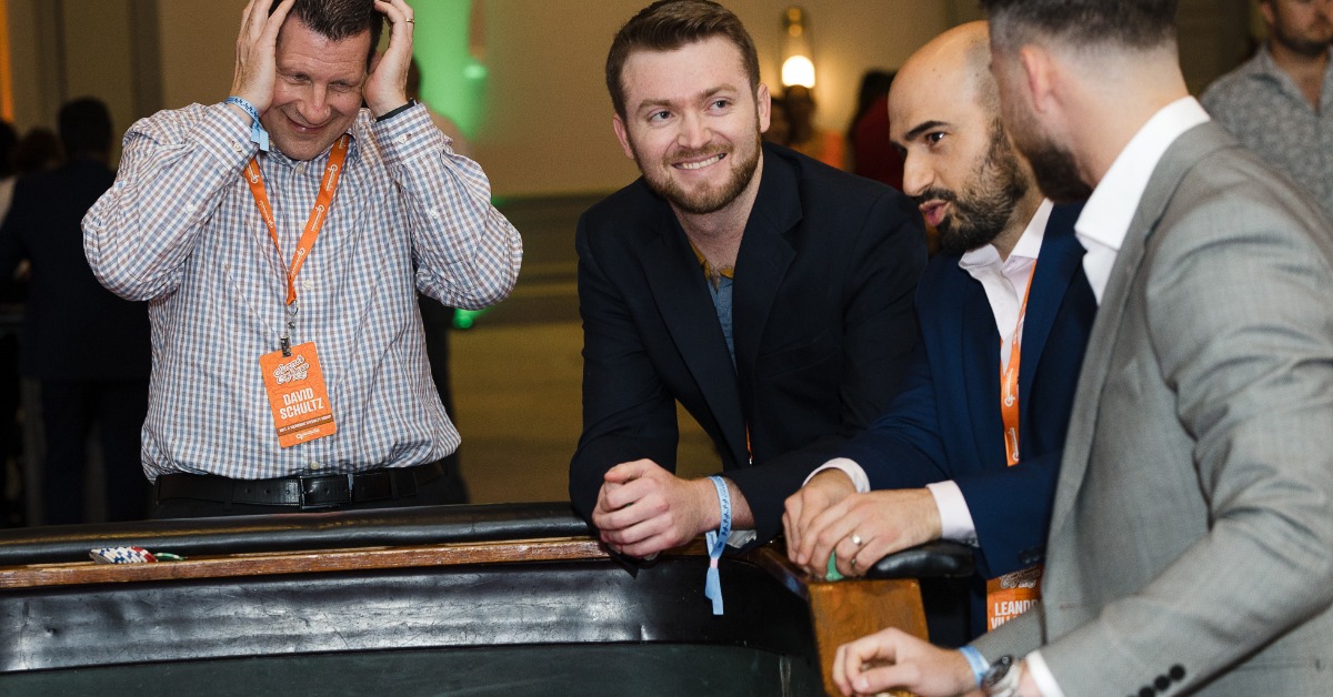 Four guests react around a craps table as one man holds his head and others watch the game during a casino charity event.